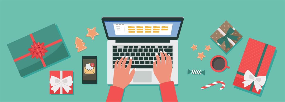 Hands typing on a laptop surrounded by wrapped gifts, cookies, candy cane, coffee, and a smartphone with email notifications.